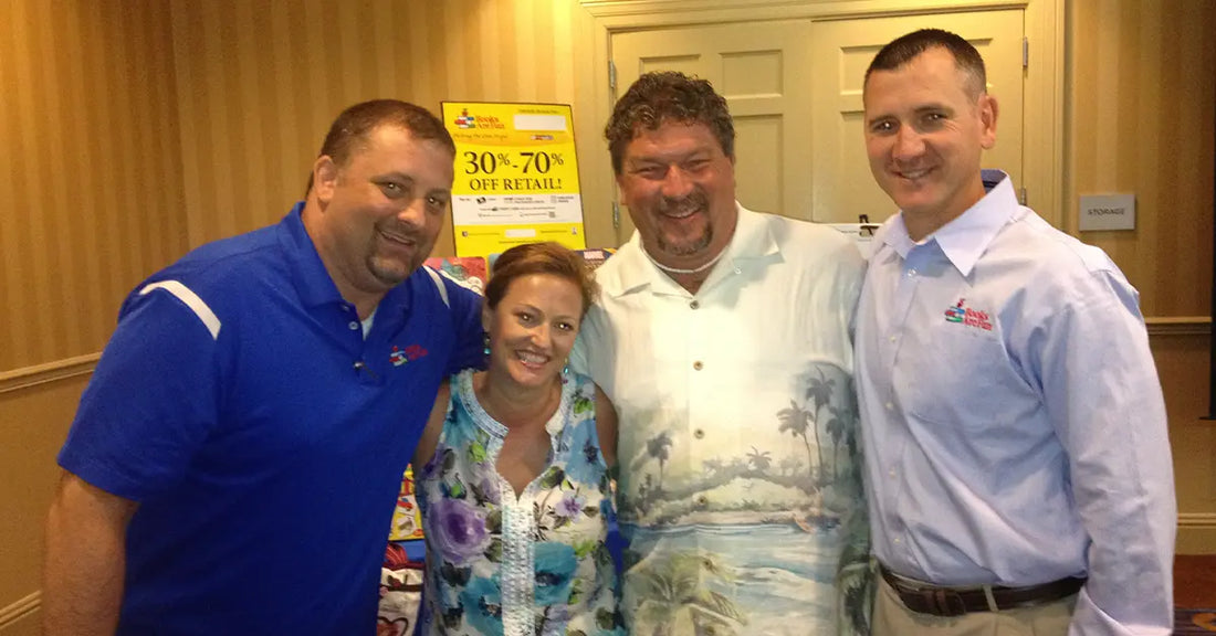 Four Books Are Fun regional representatives pose together at an award ceremony in 2013, celebrating their recognition as Regional Reps of the Year. Everyone is smiling, with one rep wearing a tropical shirt that totally stole the show.