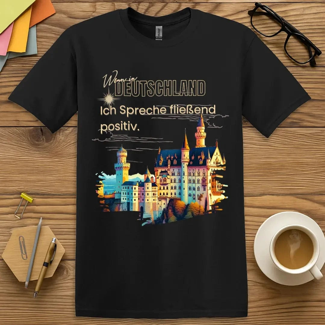 Black T-shirt with "Wenn in Deutschland Ich Spreche Fließend Positiv" design featuring colorful German castle graphic.