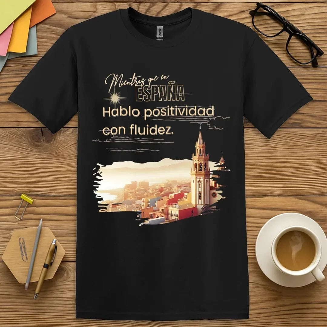 Black T-shirt with “Mientras que en España, Hablo positivo con fluidez” design featuring bold language humor for Spanish educators