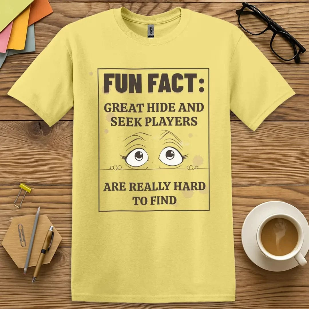 Cornsilk Color T-Shirt with "Fun Fact: Great Hide and Seek Players Are Really Hard to Find" design featuring wide-eyed cartoon peeking graphic and humor vibe.