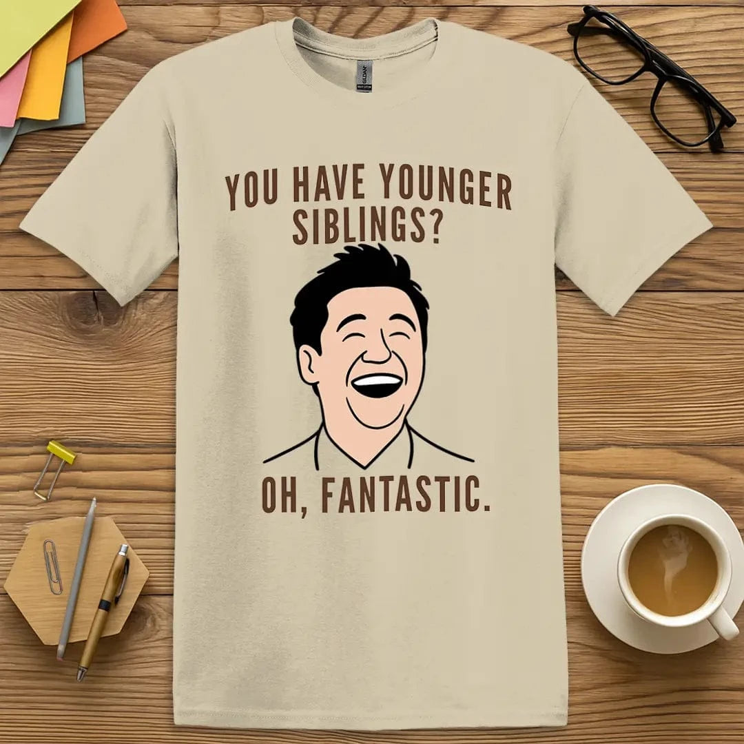 Sand T-shirt with “Younger Siblings? Oh. Fantastic.” design celebrating classroom chaos and the comedy of student sibling returns
