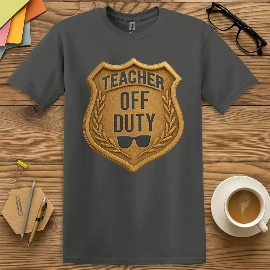 Charcoal Color T-shirt with "Teacher Off Duty" badge design featuring gold shield graphic and sunglasses, signaling relaxed authority.