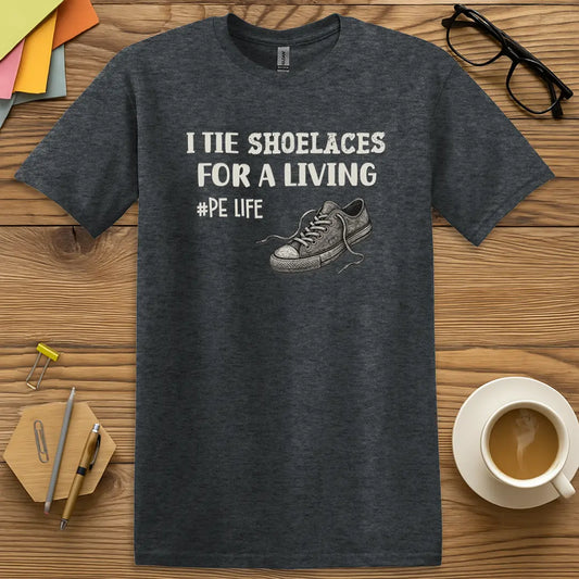 Dark Heather Color T-Shirt with "I Tie Shoelaces for a Living #PE Life" design featuring vintage sneakers and bold block text for physical education humor.