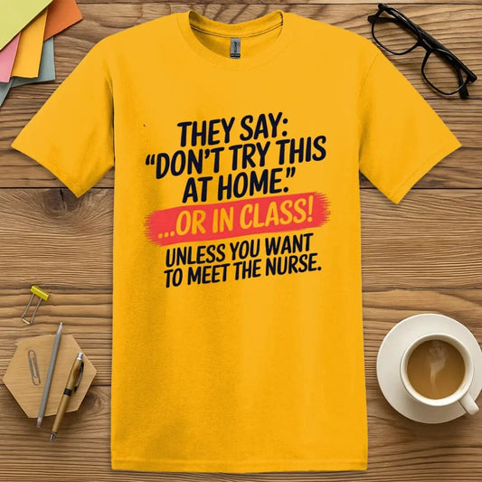 Gold T-shirt with “Don’t Try This at Home... OR IN CLASS!” design featuring bold safety-themed humor and playful educational warning