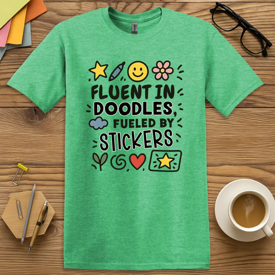 Heather Irish Green Color T-shirt with "Fluent in Doodles, Fueled by Stickers" design showing bright art room energy and creative chaos.