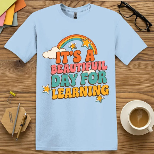 Light Blue T-shirt with “It’s a Beautiful Day for Learning” design featuring playful rainbow and stars – cheerful and bright teacher vibes