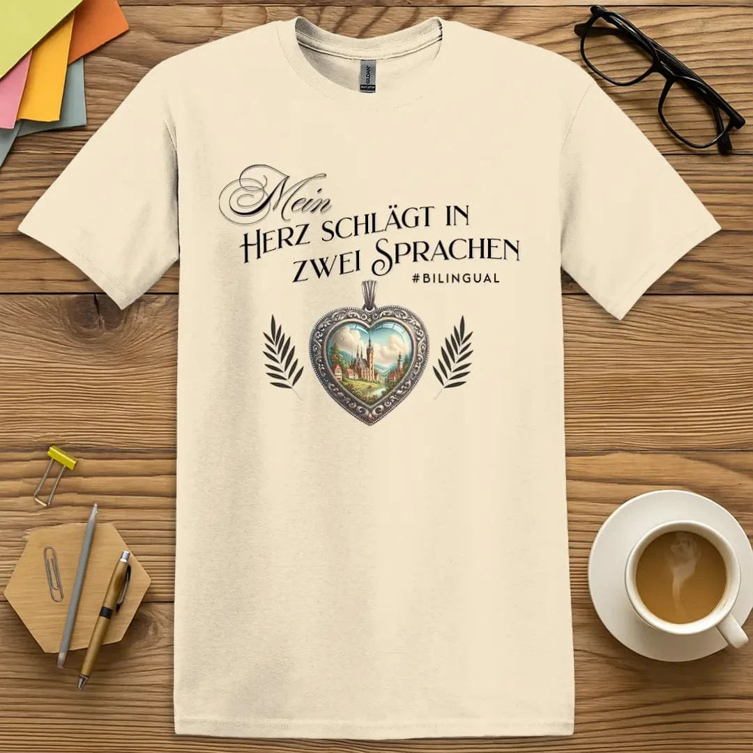 Natural T-shirt with “Mein Herz schlägt in zwei Sprachen” design featuring ornate heart and countryside for bilingual German language lovers  