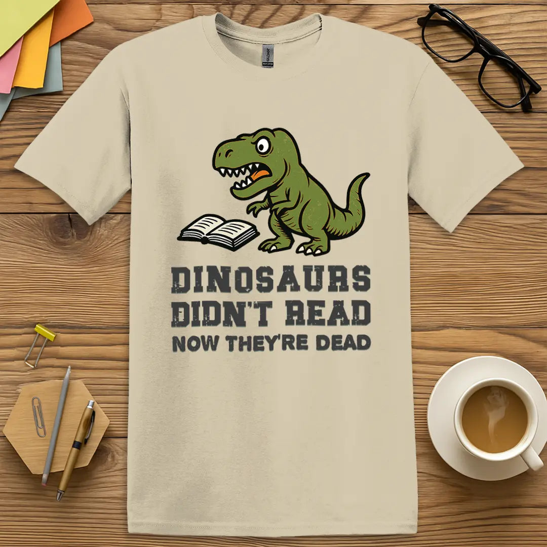 Sand T-shirt with "Dinosaurs Didn't Read Now They're Dead" design offering subtle tones and bold message for reading lovers.