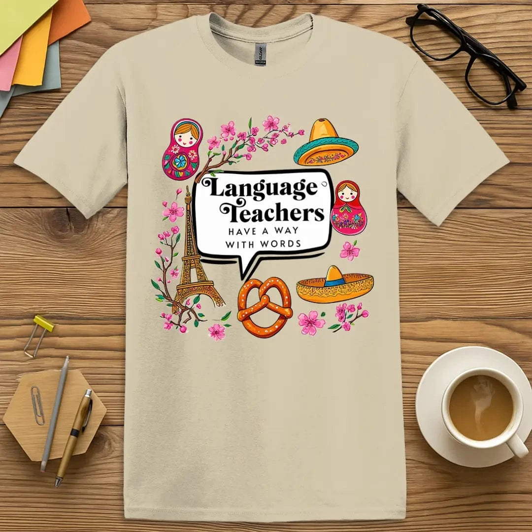 Sand T-shirt with “Language teachers have a way with words” design featuring international icons and a playful academic vibe  